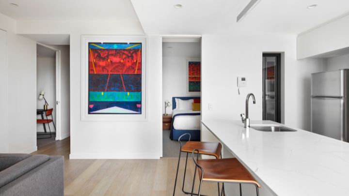 A hotel apartment with a kitchen bench and a blue and red painting